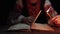 Ukrainian woman reading ancient book - Bible. Concentrated attentively follows finger on paper page under candle light