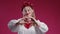 Ukrainian woman sign of shape heart. Red studio. Volunteering, charity donation.