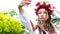 Ukrainian woman in a traditional folk image looks at the phone taking a selfie Looks in the mirror wreath white flowers