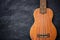 Ukulele on black cement background.