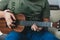 Ukulele game. a man playing a little guitar. the performer writes the music on the ukulele at home