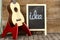 Ukulele guitar and blackboard with the word idea written on wooden background.