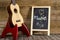 Ukulele guitar and blackboard with the word Music written on wooden background