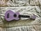 Ukulele made from wood in purple color put on soft cloth background,Hawaiian acoustic instrument