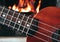 Ukulele small guitar close up stings, fireplace on the background. Musical concept, guitar fret board macro, fire in chimney, cos