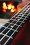 Ukulele small guitar close up stings, fireplace on the background. Musical concept, guitar fret board macro, fire in chimney, cos