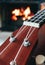 Ukulele small guitar close up stings, fireplace on the background. Musical concept, guitar fret board macro, fire in chimney, cos