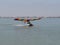 Ultralight with pontoons and colorful wings landing on water