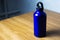 Ultramarine thermo bottle on wooden table.