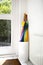 Umbrella in holder rainbow colored in white hallway, modern design in bright house next to door colorful