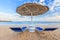 Umbrella and two empty deckchairs on the shore sand beach