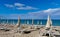 Umbrellas and sunbeds on the empty beach and a platform overlooking the sea on the horizon