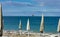 Umbrellas and sunbeds on the empty beach and a platform overlooking the sea on the horizon