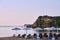 Umbrellas and sunbeds on the sandy beach and rocky peninsula