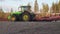 UMEA, SWEDEN - MAY 11, 2020: Green tractor plowing field, preparing land for sowing. Swedish farmer preparing field. Large red