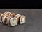 Unagi eel sushi roll with avocado and cream cheese inside roll on dark concrete background
