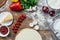 Unbaked pizza dough with fresh ingredients on wooden table