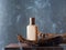 Unbranded beauty bottle in wooden hand on gray background with smoke. Essential oils