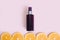 Unbranded dark brown spray bottle and line of orange slice circles on pink background. Cosmetic packaging mockup. Template, front