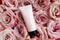 Unbranded pink squeeze bottle cream tube with black screw cap and pink roses background. Bottle for branding and label. Natural