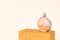 Unbranded round glass perfume bottle on golden podium on ivory background. Eau de toilette. Mockup, copy space