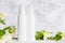 Unbranded skincare products plastic bottle with dispenser and flacons. Tube for cream shampoo. Green jasmine flowers and their