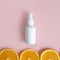 Unbranded white plastic spray bottle and orange slices border on pink background. Mockup. Skincare beauty and liquid antibacterial