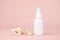 Unbranded white plastic spray bottle and two sea shells on pink background. Mockup. Skincare beauty and liquid antibacterial spray