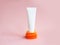Unbranded white squeeze cosmetic tube on stack of orange slices. Cosmetic skincare product blank plastic package on pink