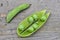 Uncapped pod of fresh green peas on wooden table close-up