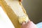 Uncapping honey cells with a fork. Professional beekeeper holds wooden frame with bee honeycomb in his hands, collects