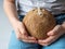 Uncertain child in blue shorts holds in his hands a young coconut with drinker