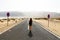 Uncertain future. Young alone woman advances with an uncertain step in empty asphalt desert road. Apocalypse concept