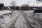 An unclean dirt road with a track is littered with snow in the village there is no passage in the spring