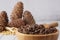 Uncleaned pine nuts in a bowl with a wooden spatula, cedar cones on a wooden table