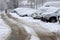 Uncleaned streets with heavy snowdrifts after snowfall in the city, cars under the snow