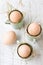 Uncolored natural easter eggs in espresso cups; happy easter concept; white wooden background