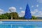 Unconventional blue christmas tree in green tropical garden with swimming pool