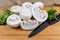 Uncooked button mushrooms, parsley and kitchen knife on cutting board