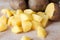 Uncooked cubical yellow potatoes and fresh raw potatoes on chopping board.