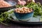 Uncooked dried chickpeas in dish with raw green chickpea plants on wooden table