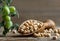 Uncooked dried chickpeas in wooden shovel with raw green chickpea pod plant on wooden table