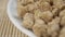 Uncooked dried soybeans close-up in a white bowl on a traditional bamboo mat.