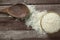 Uncooked dry Thai jasmine rice are overflow from bowl and wooden ladle beside put on wood floor, top down horizontal view.