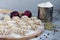 Uncooked, frozen dumplings on a wooden board. In the background is a metal mug with flour, next to pepper, greens and onions on a