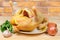 Uncooked gutted carcass of broiler and vegetables on rustic table