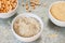 Uncooked half peas, rice and millet in white ceramic bowl above view on metal background