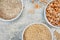 Uncooked half peas, rice and millet in white ceramic bowl on metal background