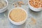 Uncooked half peas, rice and millet in white ceramic bowls on metal background