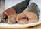 Uncooked headless hake fishes lie on a plate, cropped image